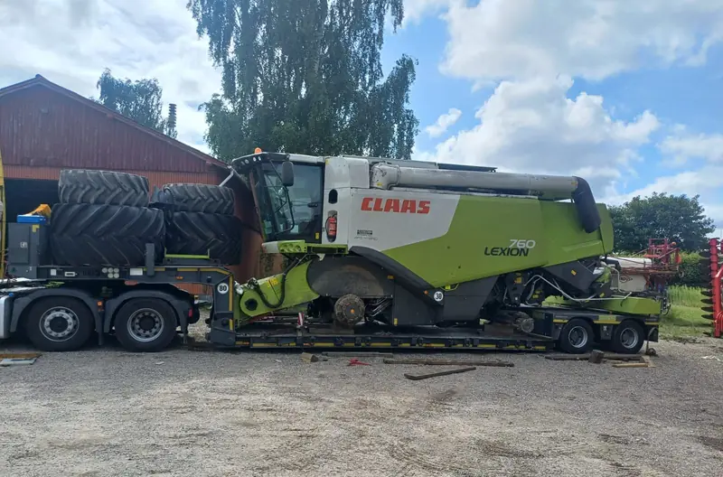 Combină Claas Lexion pe trailer agabaritic, cu roțile mari demontate și încărcate separat