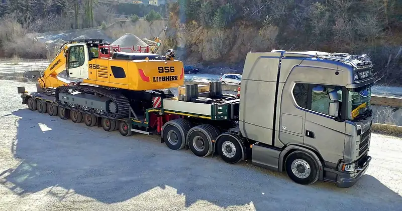 Excavator pe șenile Liebherr încărcat pe trailer cu platformă joasă, tras de un Scania